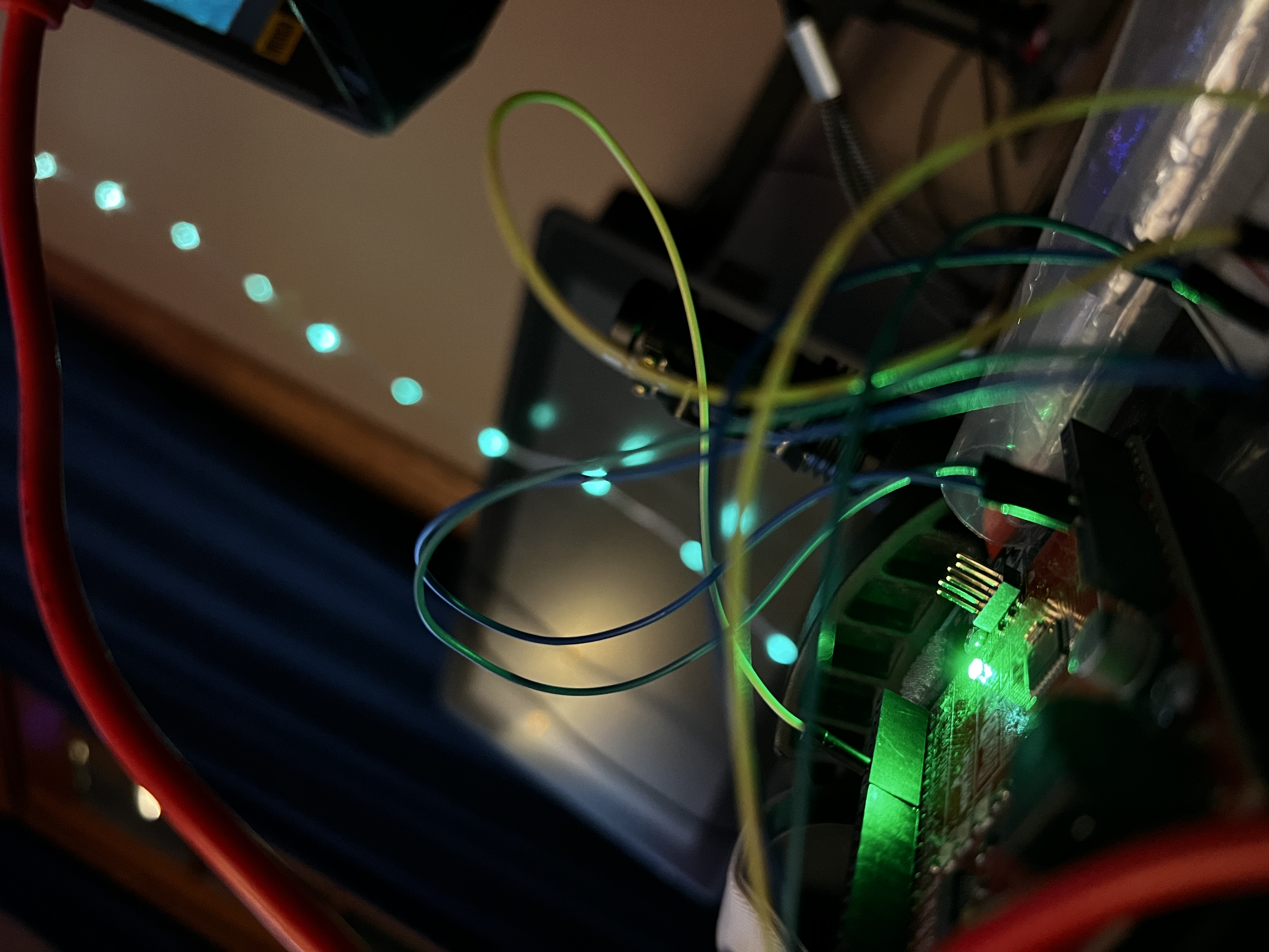 Addressable LED strands glowing green and cyan in a dim room, wired to a small microcontroller on a breadboard.
